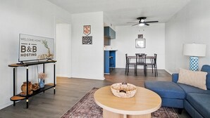 Una sala moderna con una mesa redonda de madera, un sofá azul y un comedor con mesa y sillas.