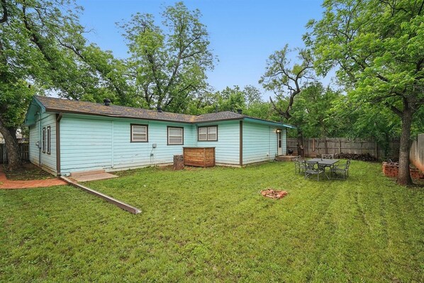 A single-story house with a front yard and a small patio area. - Vibrant Artistic Retreat Among the Trees (Abilene)
