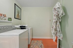 A laundry room with a washing machine, dryer, and a hanging rack.