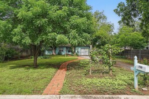 A residential property with a brick pathway leading to a house, a mailbox, and a fenced yard.