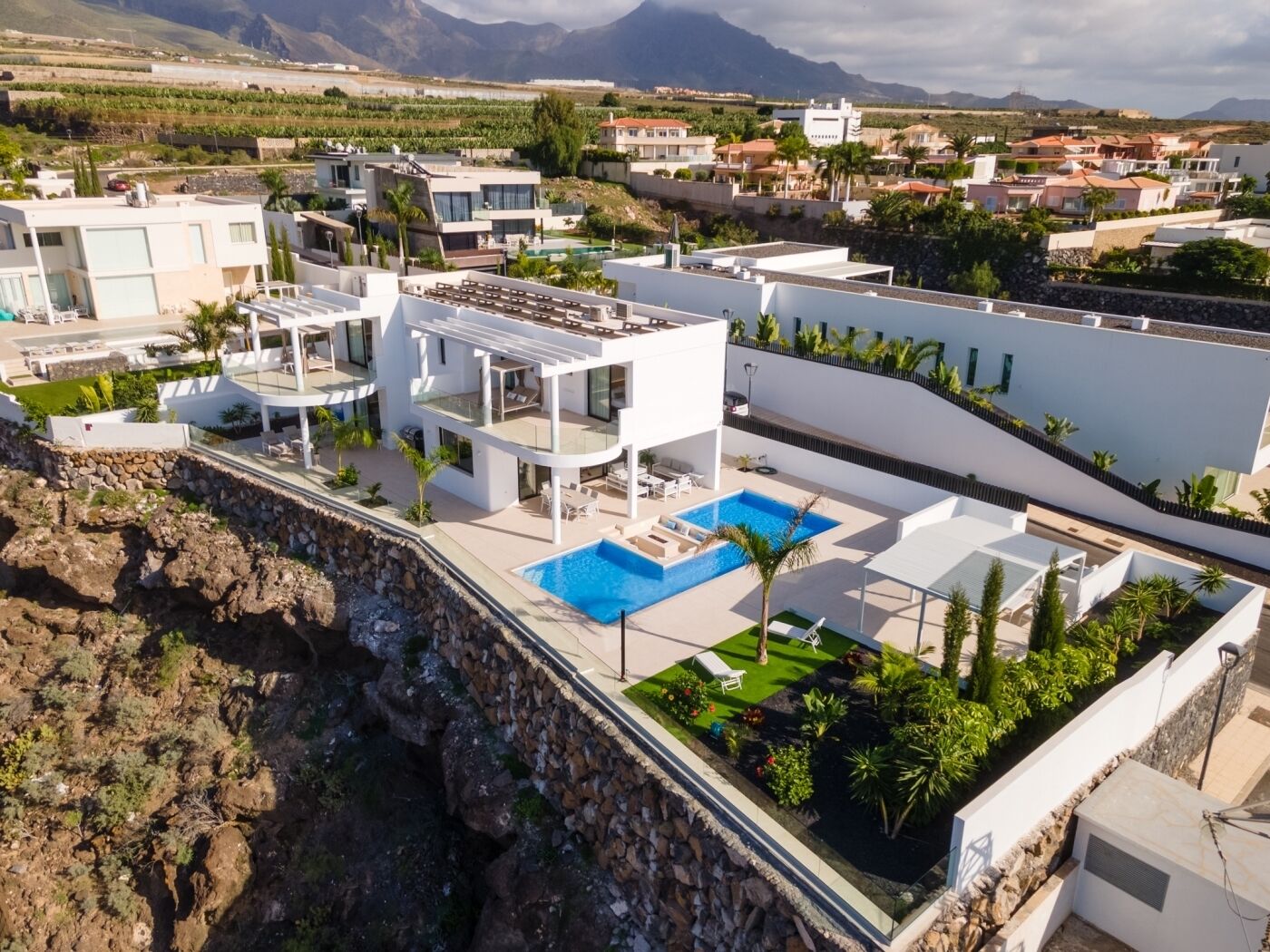 Una villa moderna con piscina, varios balcones y vistas del paisaje circundante.
