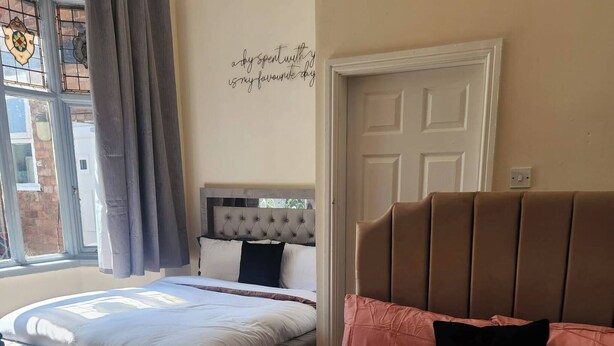 Une chambre avec deux lits, une fenêtre avec des rideaux et une porte.