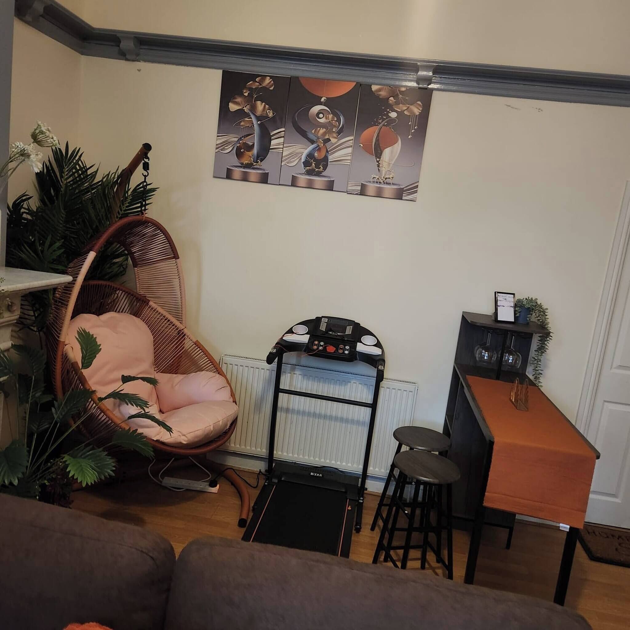 Een gezellige zithoek met een hangstoel, een loopband en een kleine bar.