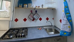 A kitchen with a skylight, a gas stove, a sink, and a window.