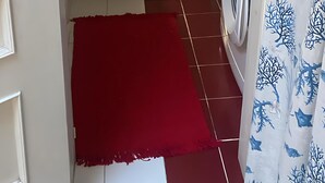 A compact bathroom with a white sink, toilet, and washing machine. There is a red rug on the floor and a blue rug near the sink.