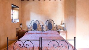 Un dormitorio con cama, mesita de noche, lámpara y ventana.