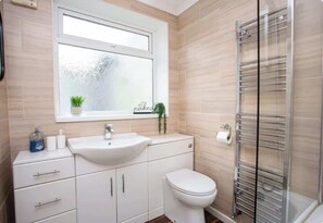 Ein Badezimmer mit Waschbecken, Toilette, einem Fenster mit satiniertem Glas und einem Handtuchhalter.