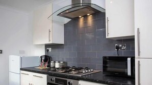 Eine moderne Küche mit weißen Schränken, einem Gasherd, einem Backofen, einer Mikrowelle und einer Edelstahl-Dunstesse.