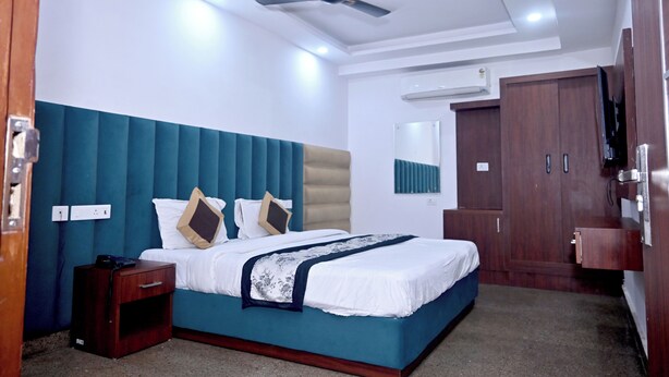 Een hotelkamer met een bed, nachtkastje, garderobe en plafondventilator.