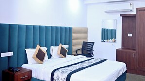 Een slaapkamer met een groot bed, een nachtkastje, een stoel, een plafondventilator en een garderobe.
