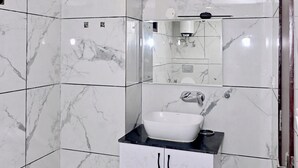 Een badkamer met witte marmeren tegels, een witte wastafel en een spiegel erboven.