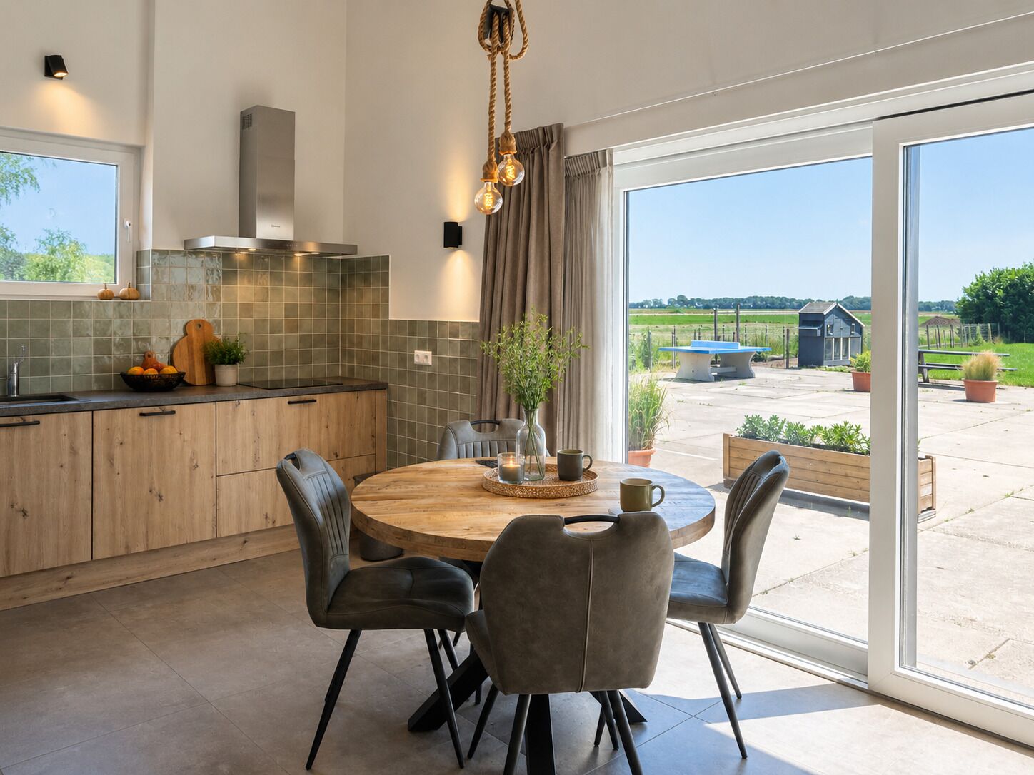 A modern kitchen with a round dining table, chairs, and a view of the outdoors.
