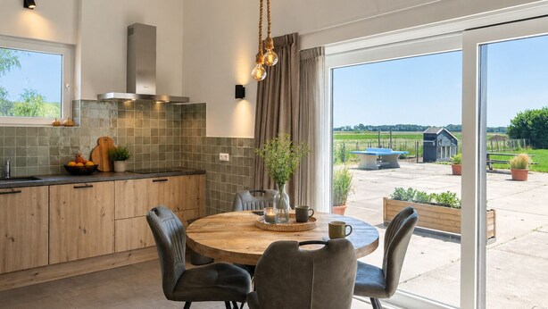 Une cuisine moderne avec une table à manger ronde, des chaises et une vue sur l’extérieur.