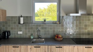 A modern kitchen with a window, a sink, a coffee maker, and a fruit bowl. - Luxury Hay Barn Holiday Home with Open Countryside Views in the Green Heart (Alphen aan den Rijn)