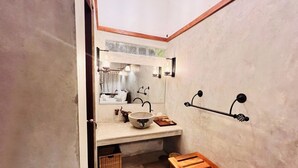 A bathroom with a wooden bench, a large mirror, a sink with a bowl, and wall-mounted towel racks. - Yala Leopard Lodge (Kirinda)