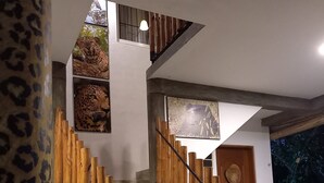 A staircase with wooden railings and a metal handrail, leading to a landing with a door and a wall-mounted picture. - Yala Leopard Lodge (Kirinda)