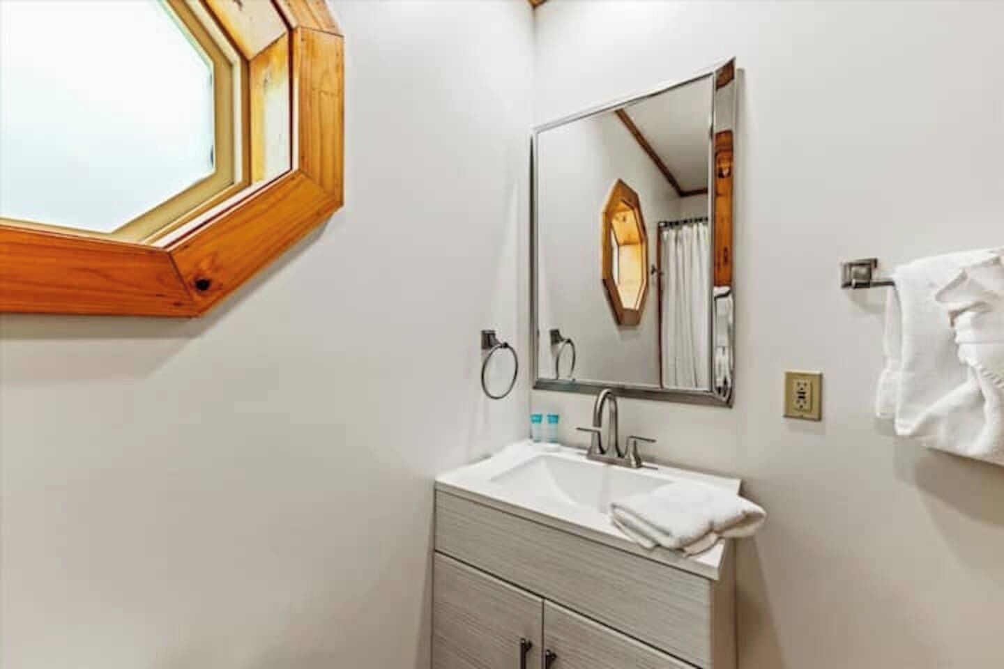 Une salle de bain avec une fenêtre à cadre en bois, un lavabo avec un miroir et un porte-serviettes.