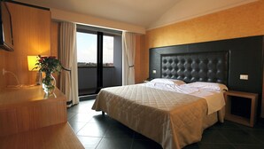 Une chambre d’hôtel avec un lit, une table de chevet, une lampe et une vue sur l’extérieur.