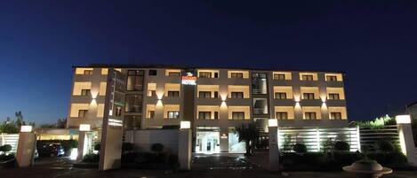 A multi-story hotel with a modern design, featuring a central entrance and illuminated signage.