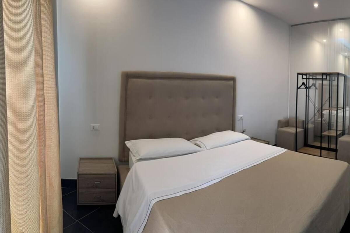 A bedroom with a bed, bedside tables, a wardrobe, and a bathroom with a glass partition.