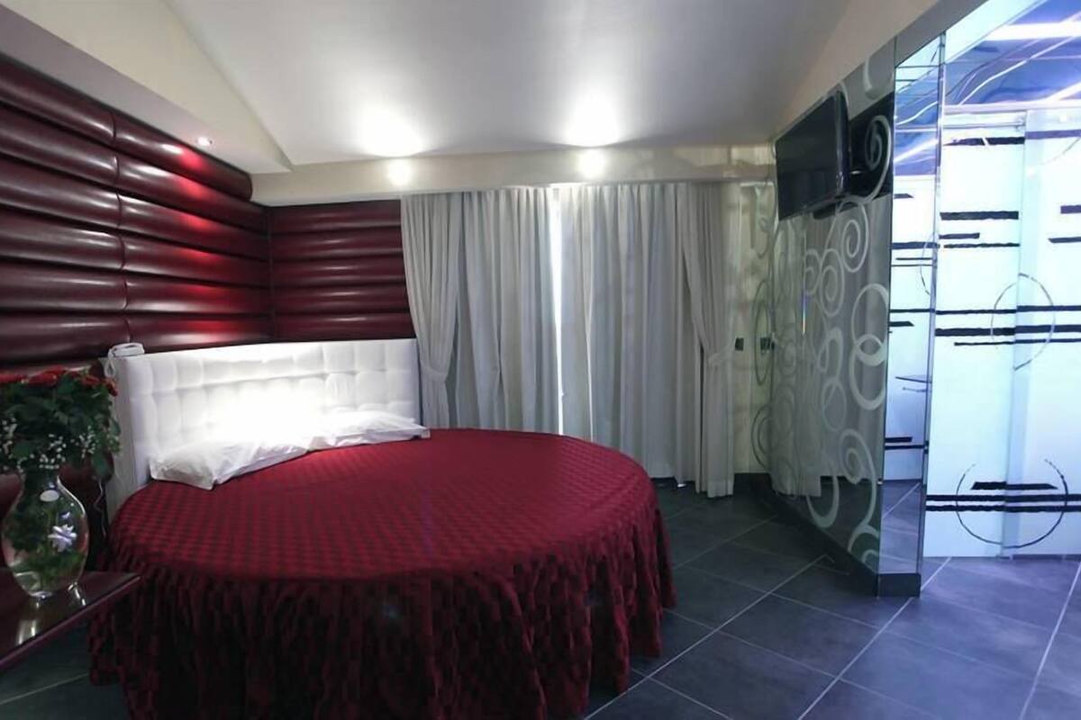 A modern bedroom with a large bed, a red and white color scheme, and a television on the wall.