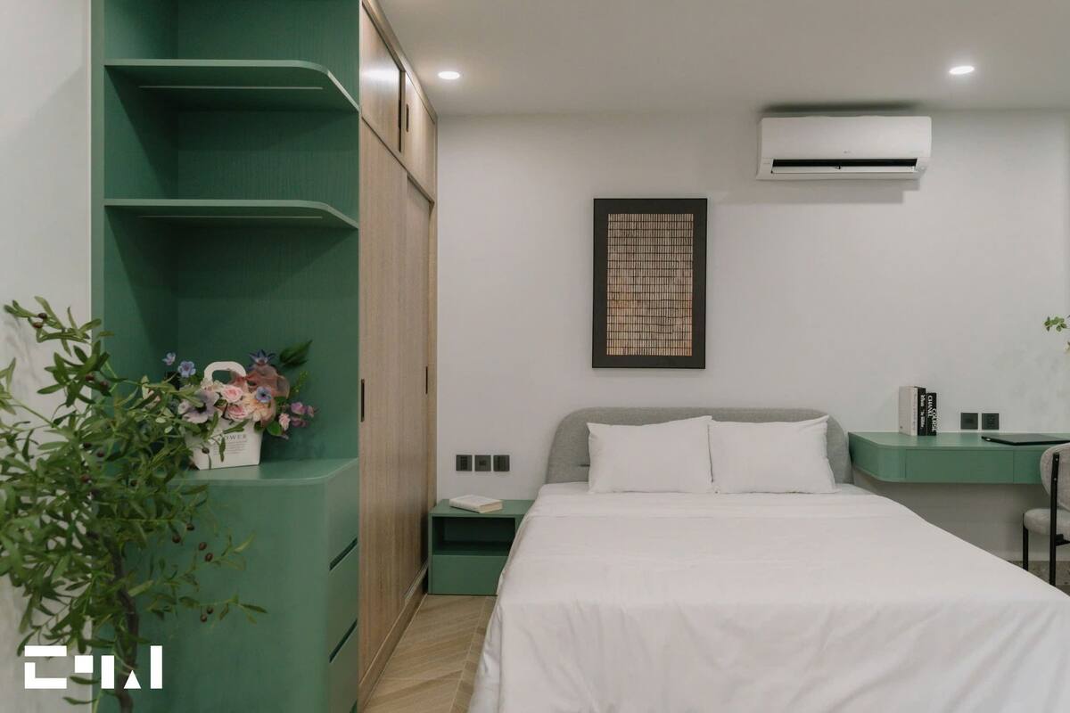 Een moderne slaapkamer met een bed, een bureau en een groen schapenkast.