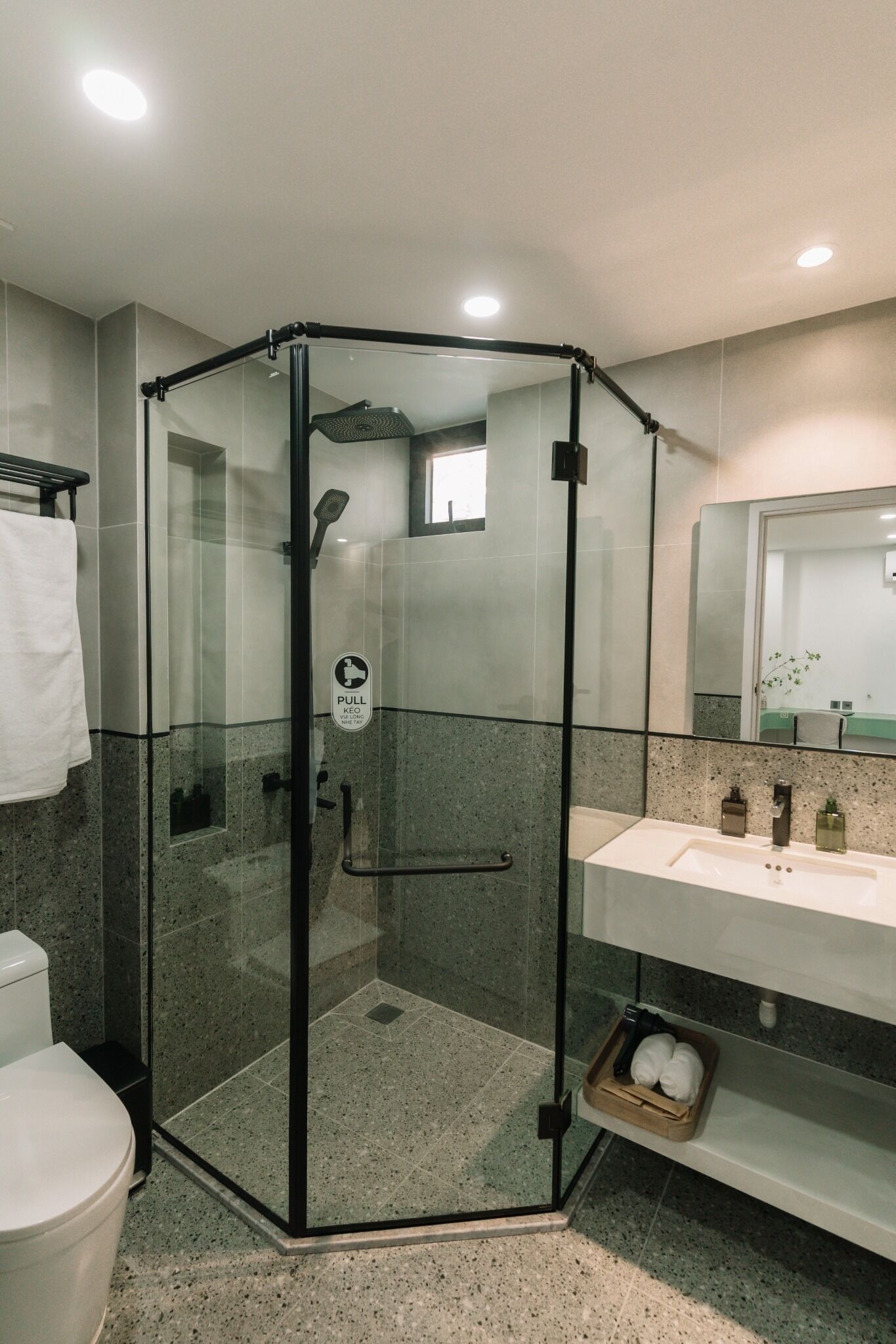 A modern bathroom with a glass-enclosed shower, a white sink, and a mirror.
