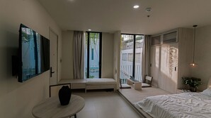A modern hotel room with a bed, a small table, a seating area, and a TV mounted on the wall.