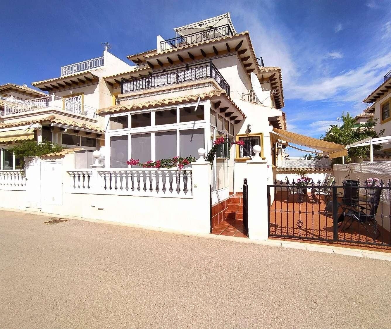 A two-story house with a balcony, a gated patio, and a clear blue sky.