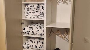 A wardrobe with multiple shelves, some with hanging space, and a few hangers visible.