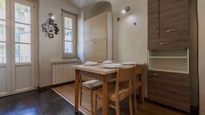 Un comedor con una mesa y sillas de madera, una ventana con persianas y un armario empotrado de madera.