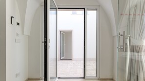 Una habitación de hotel moderna con una puerta de vidrio que da a un balcón, una zona de ducha y un baño a la vista.