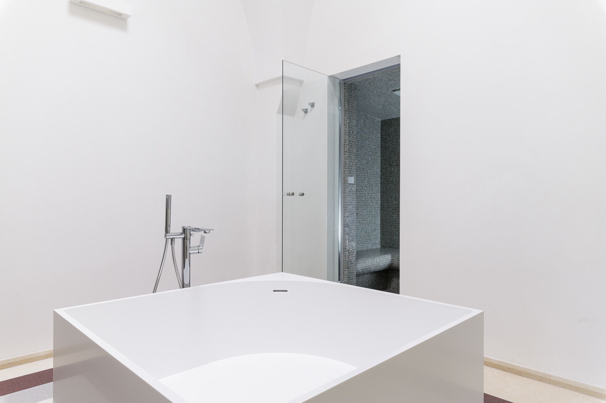 Une salle de bain moderne avec une baignoire blanche, une cabine de douche en verre et un espace de douche carrelé.