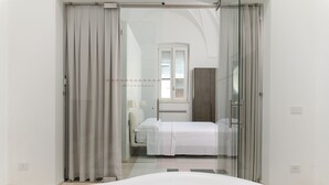 Ein modernes Schlafzimmer mit Bett, Nachttisch, Fenster und einer mit Vorhängen versehenen Tür.