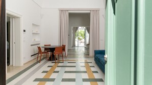 A modern room with a dining area, a sofa, and a view of the outdoors. - Hydeout Luxury Suite - Botte 14 by Wonderful Italy (San Vito dei Normanni)