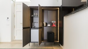 A compact kitchen with a built-in coffee machine, a small refrigerator, and a coffee maker on the countertop. - Hydeout Luxury Suite - Botte 14 by Wonderful Italy (San Vito dei Normanni)