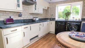 A kitchen with white cabinets, a toaster, a washing machine, and a window with a view of greenery.