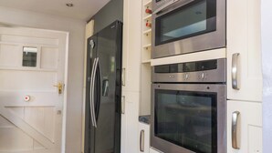 A kitchen with a stainless steel refrigerator, double oven, and white cabinetry.