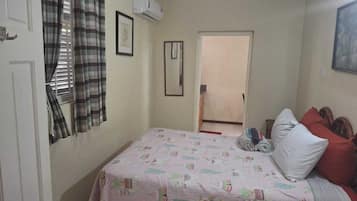 Een slaapkamer met een bed, een deur en een airconditioning.