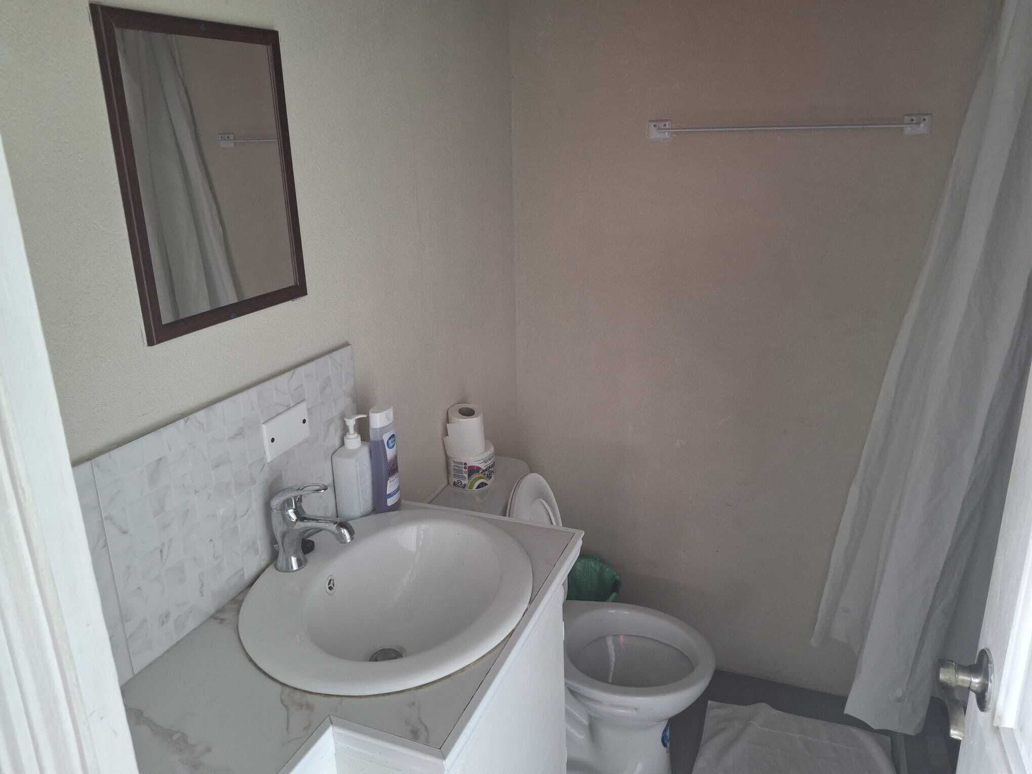 A small bathroom with a white sink, a mirror, a toilet, and a towel rack.