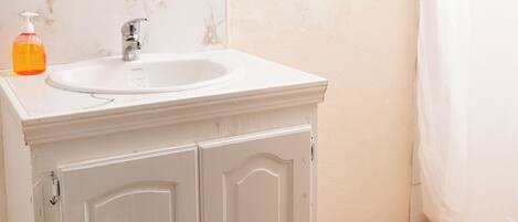 Une salle de bain avec un lavabo blanc, un miroir et un rideau de douche.