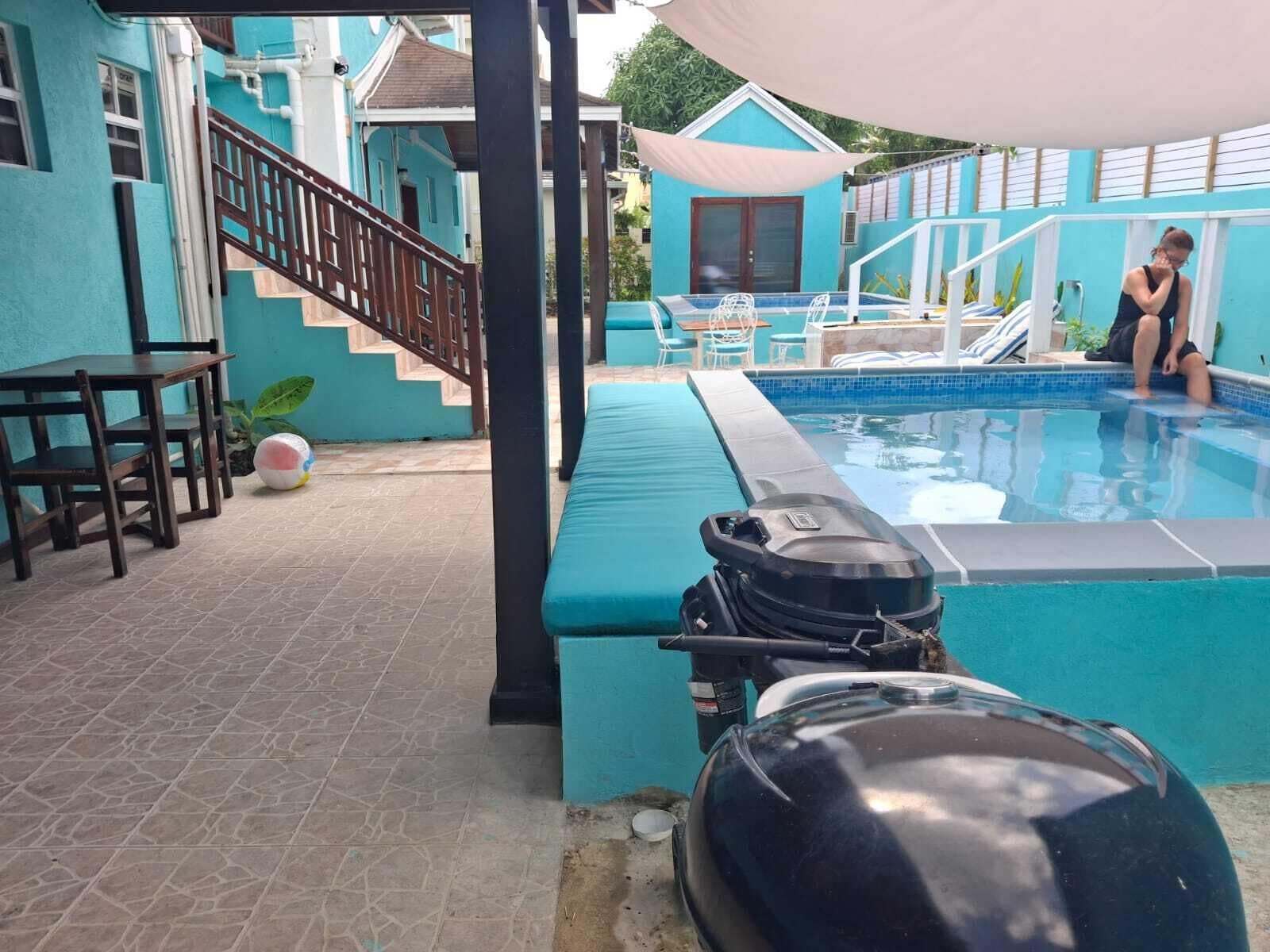 Un espace piscine doté d’un coin salon couvert, d’un barbecue et d’un escalier menant à un niveau supérieur.