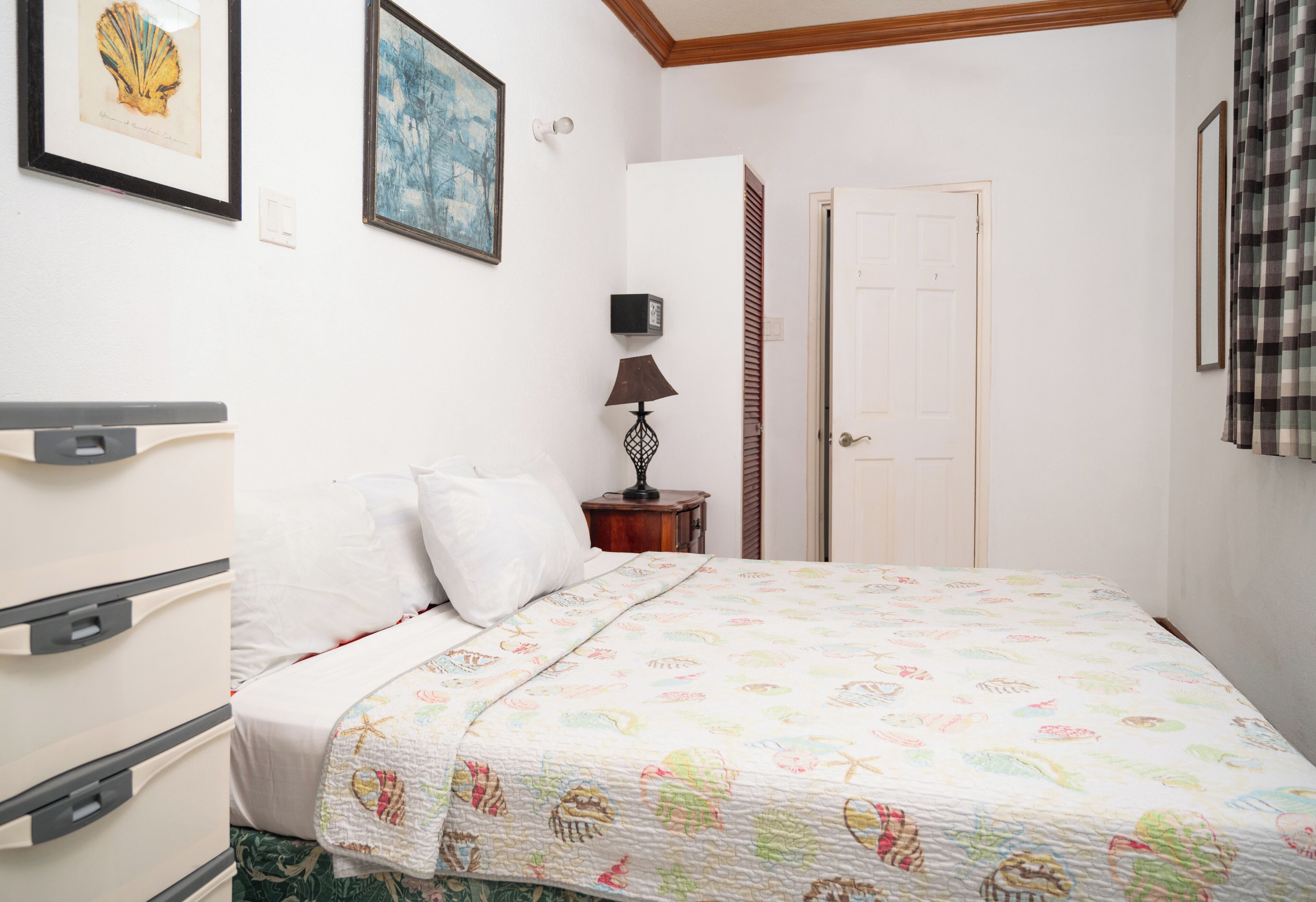 A bedroom with a bed, a dresser, a lamp, and a door.