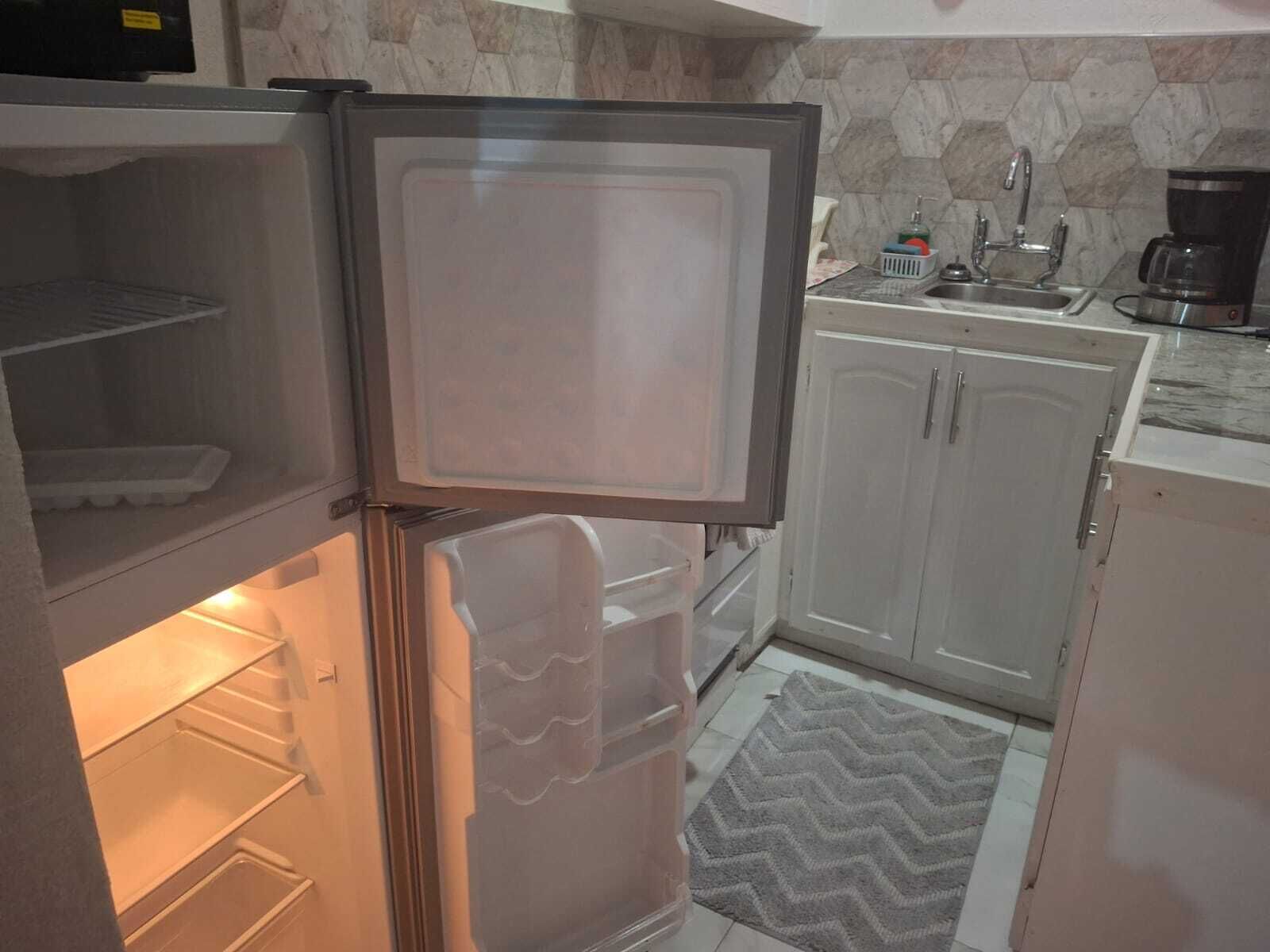 A kitchen with a refrigerator, a sink, and cabinets.