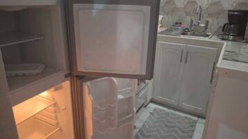 A kitchen with a refrigerator, a sink, and cabinets.