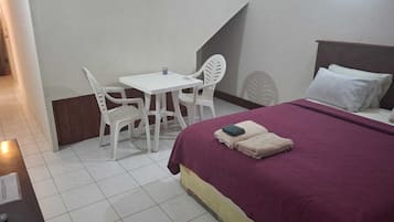 A hotel room with a bed, a desk, and two chairs.