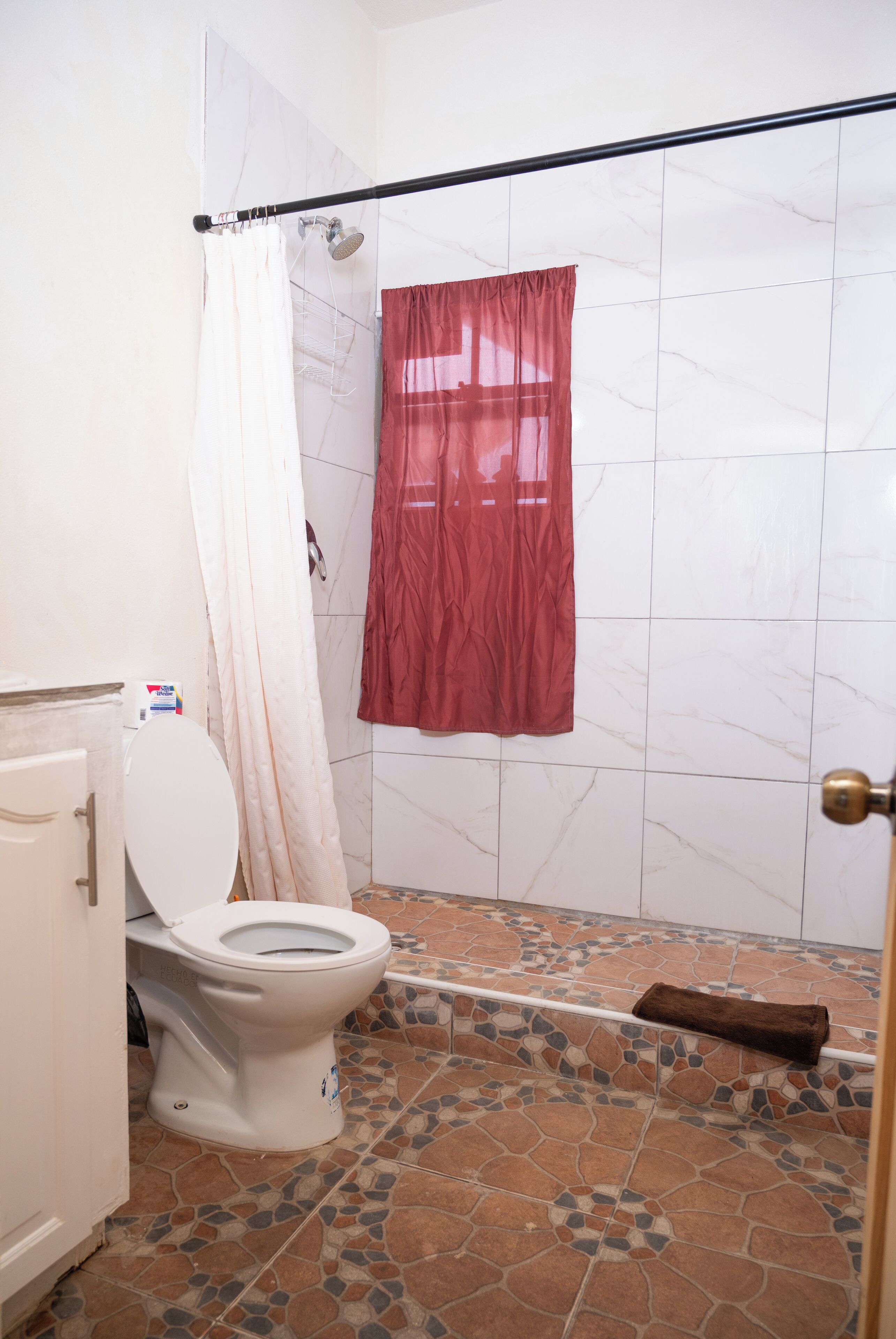 Ein Badezimmer mit Toilette, Duschvorhang und Fliesenboden.