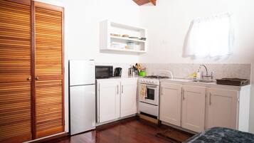 A compact kitchen with white cabinets, a microwave, a stove, and a sink.