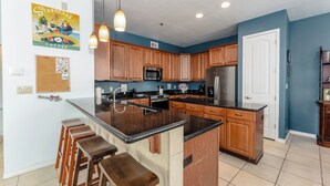 Una cocina moderna con armarios de madera, una isla central, taburetes de bar y un letrero de Starbeaks Coffee.