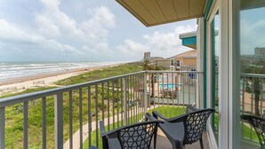 A balcony with a view of the beach and ocean.